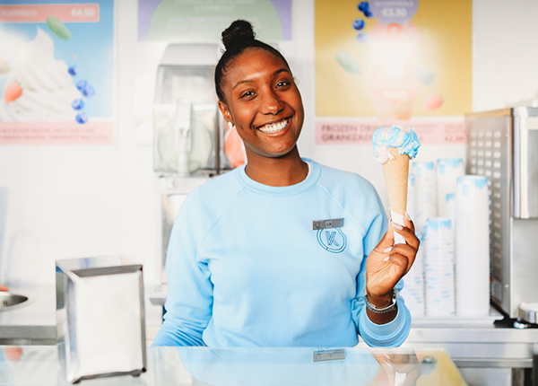 Woman holding an ice cream cone behind the counter at a shop