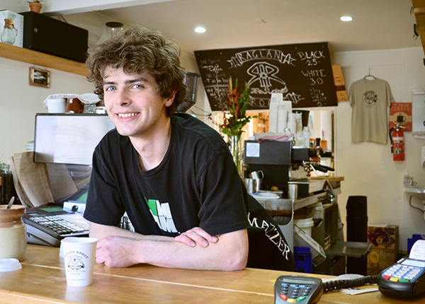 Young man behind coffee shop counter