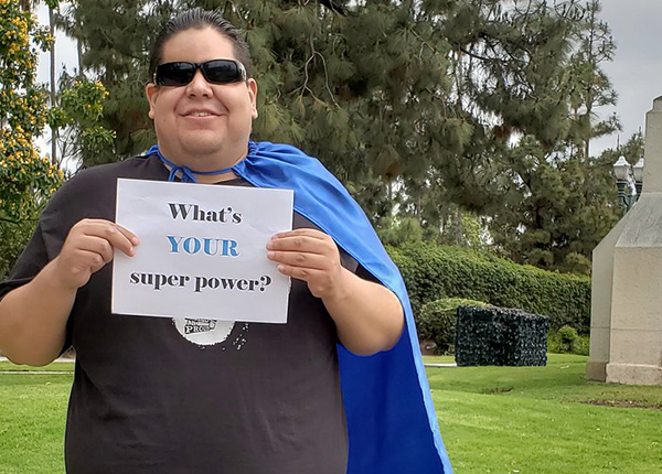 Man holding a sign that says What's Your Superpower?