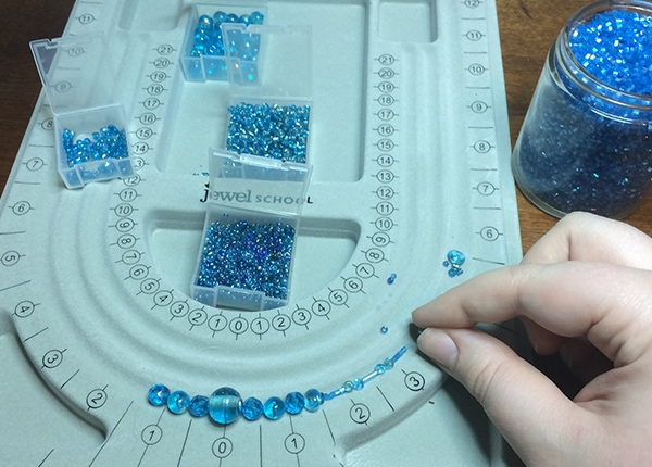 Person making a necklace with blue beads
