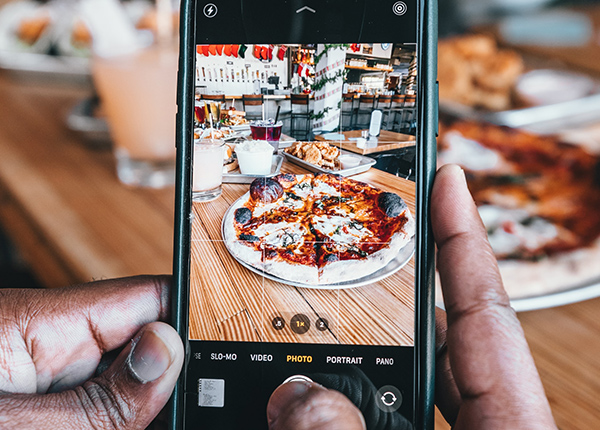 Person takes photo of pizza with cell phone