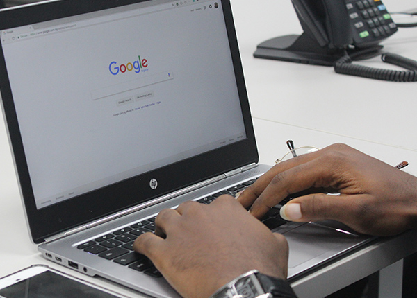Person using a laptop looks at Google search engine on the screen