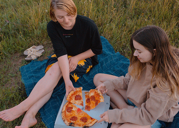 Two young people have a picnic with a pizza
