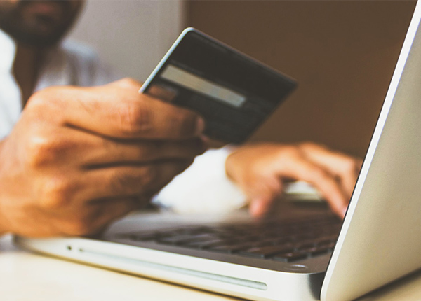 Person at computer holding a credit card