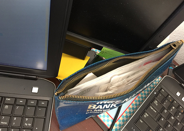 Bank bag filled with receipts next to computer