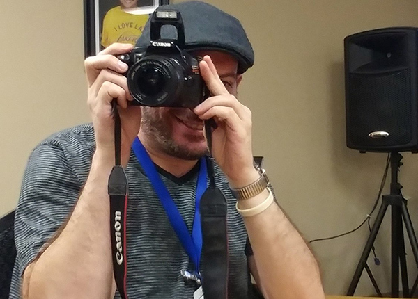 Man looking through a cameras viewfinder and smiling