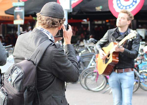 Man taking a photograph of a busker in the street