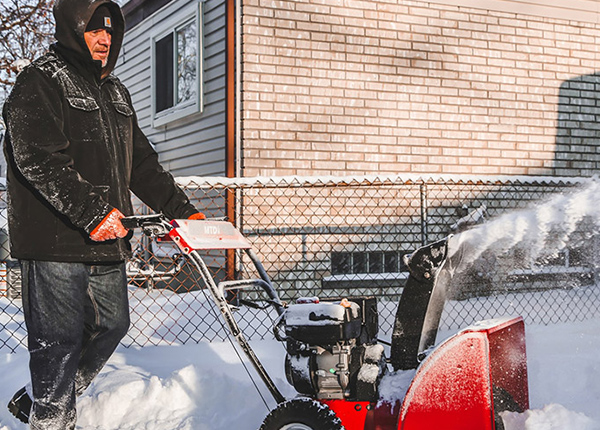 Man using a snowblower to plow sidewalk