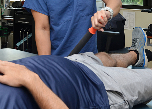 Man laying down while a health professional massages his knee