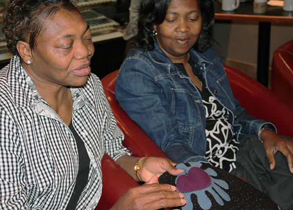 Two women looking at a stitched design on a piece of fabric