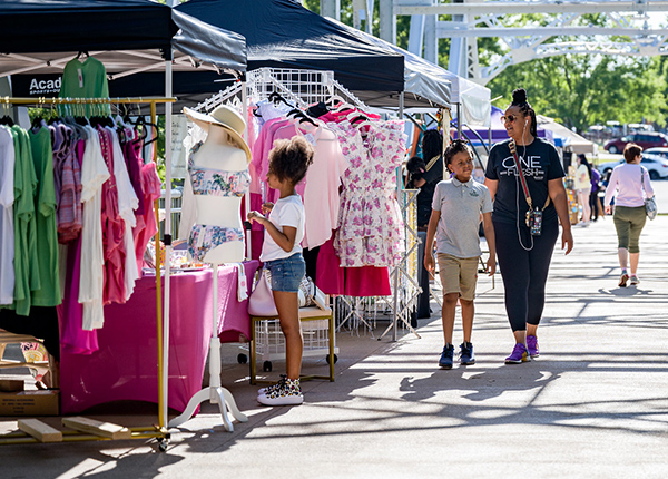 People shopping at a vendor booth selling clothing at an outdoor market