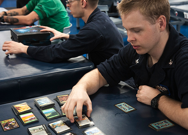Young men sit at tables with cards at a game tournament