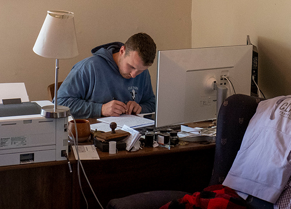 Man sitting behind computer writing in notebook