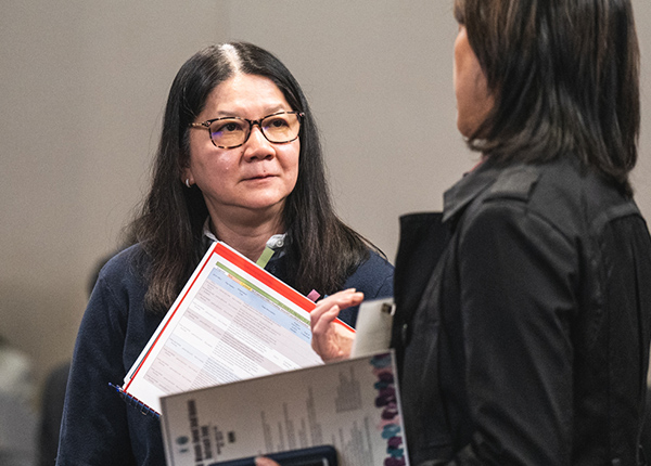 Two women talking and holding papers