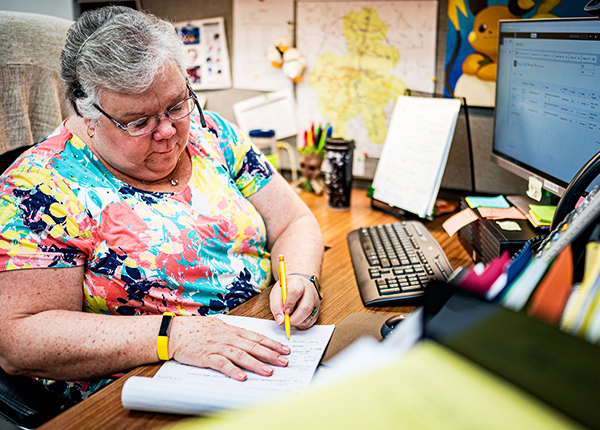 Woman sitting at an office desk writing in a notepad