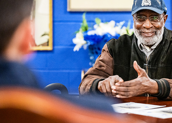 An older man talking to someone at a table