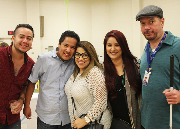 Five people smile and pose for a picture
