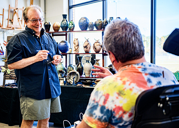 Person who uses a wheelchair talking to a man at a craft fair