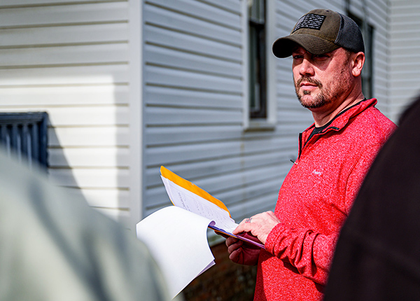 Man standing outside of a building flipping through a folder of paperwork
