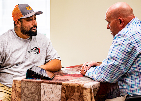 Two men sitting across a table from each other engaged in conversation