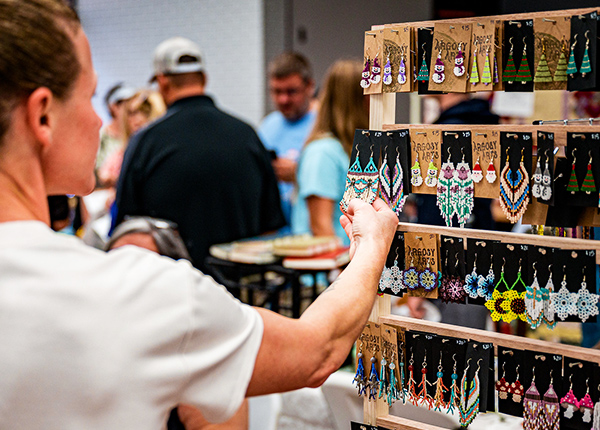 Person looking at beaded earrings at a craft show