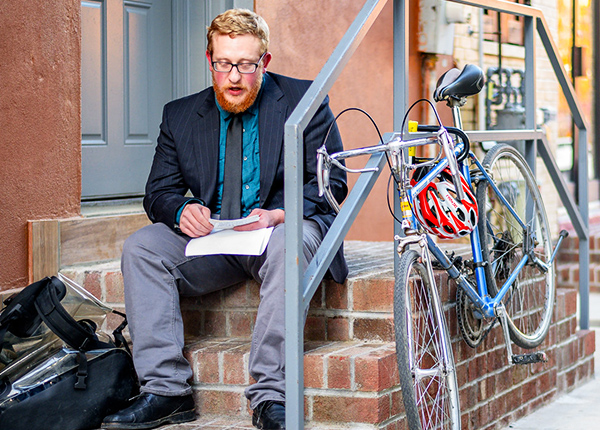 Man sitting on steps holding papers and looking at notecards