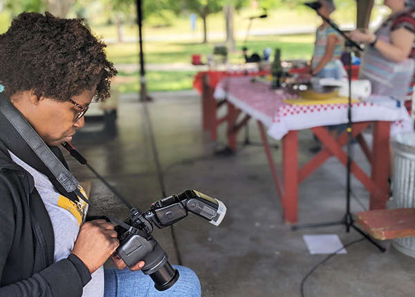 Person sitting down looking at the professional camera around their neck
