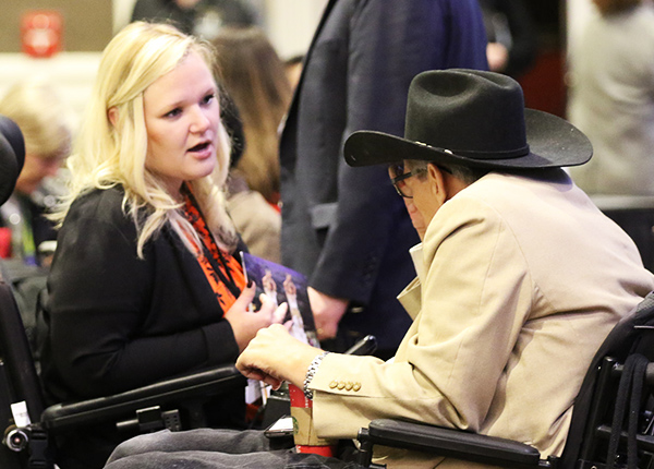 Two people who use wheelchairs engaged in conversation