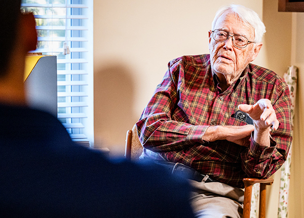 Older man sitting in a chair having a conversation with someone