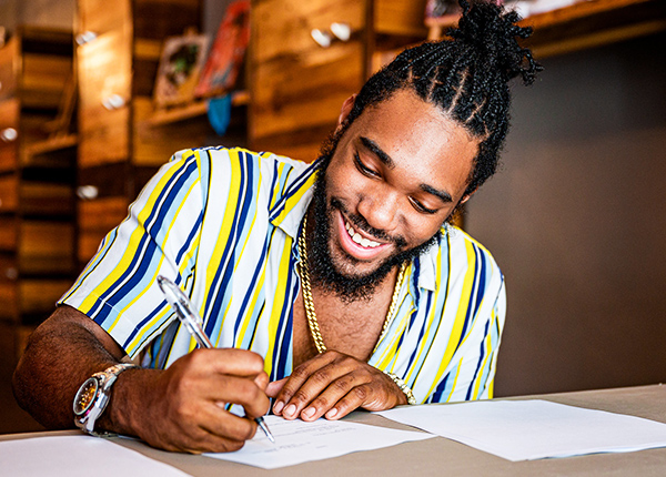 Man smiling as he writes on a piece of paper