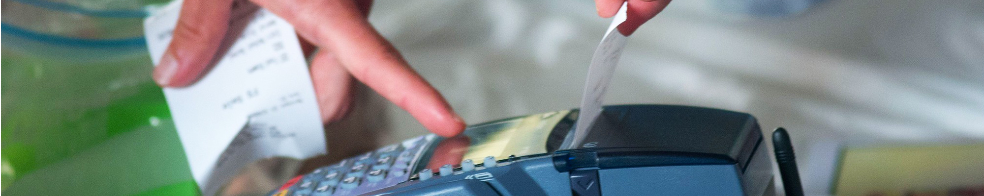 Close-up of hands pulling a receipt out of a payment terminal