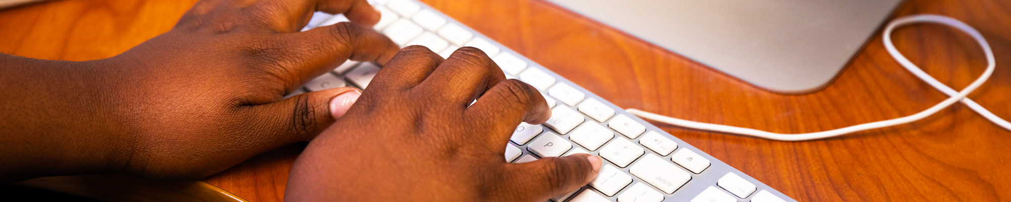 Banner image: Close-up of hands typing on a computer keyboard