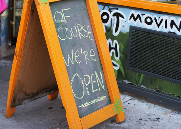 Sign outside of business that says Of Course We're Open