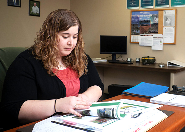 Woman sitting at an office desk flipping through a binder