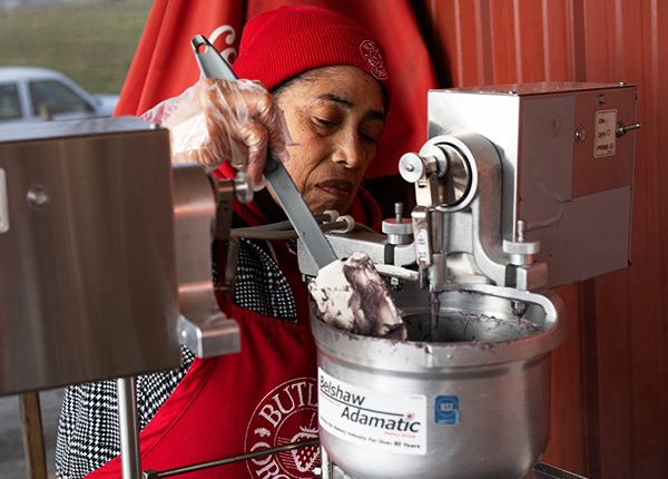 Woman using a rubber scraper to clean the edges of an industrial grade mixer