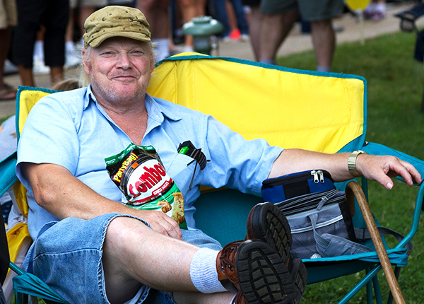 Man smiling and sitting in a folding camp chair with his feet propped up