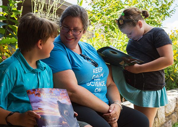 A mother sitting on a bench with her two young children