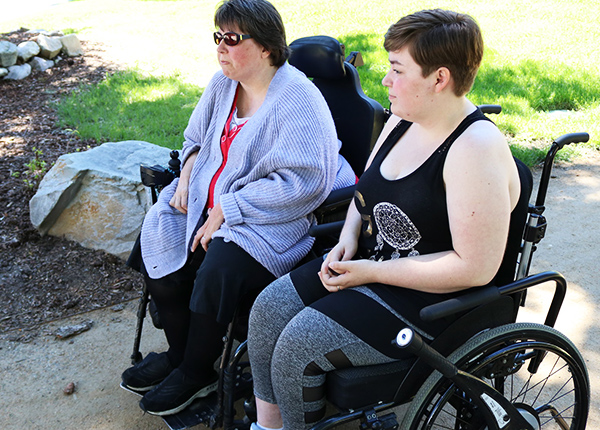 Two people who use wheelchairs in a park