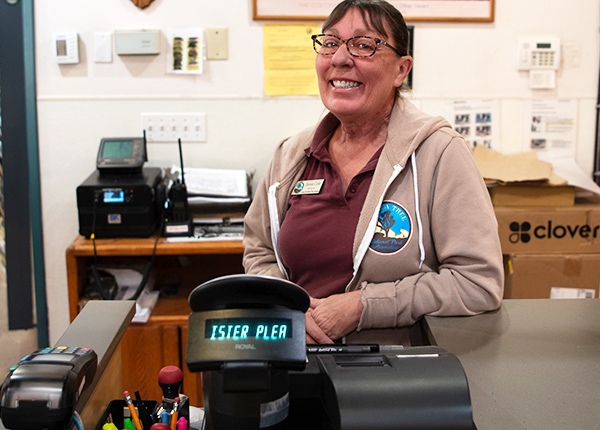 Woman with a big smile standing behind a cash register