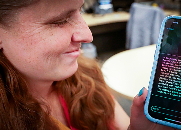 Woman with a visual impairment holding up a smart phone that uses assistive technology