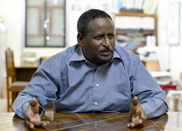 Man sitting at a table with a inquisitive look on his face and hands in a questioning gesture