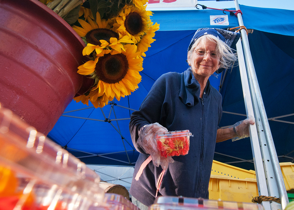 Woman setting strawberries out for sale at a farmer's market