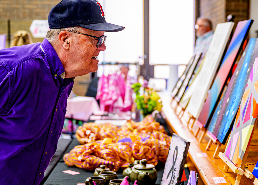 Man leaning in to look at artwork at a craft fair