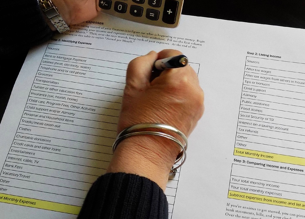 Person using a calculator and writing on a worksheet