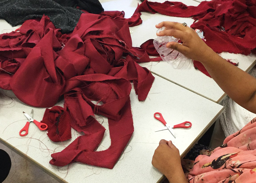 Person grabbing fabric scraps that are in a pile on a table