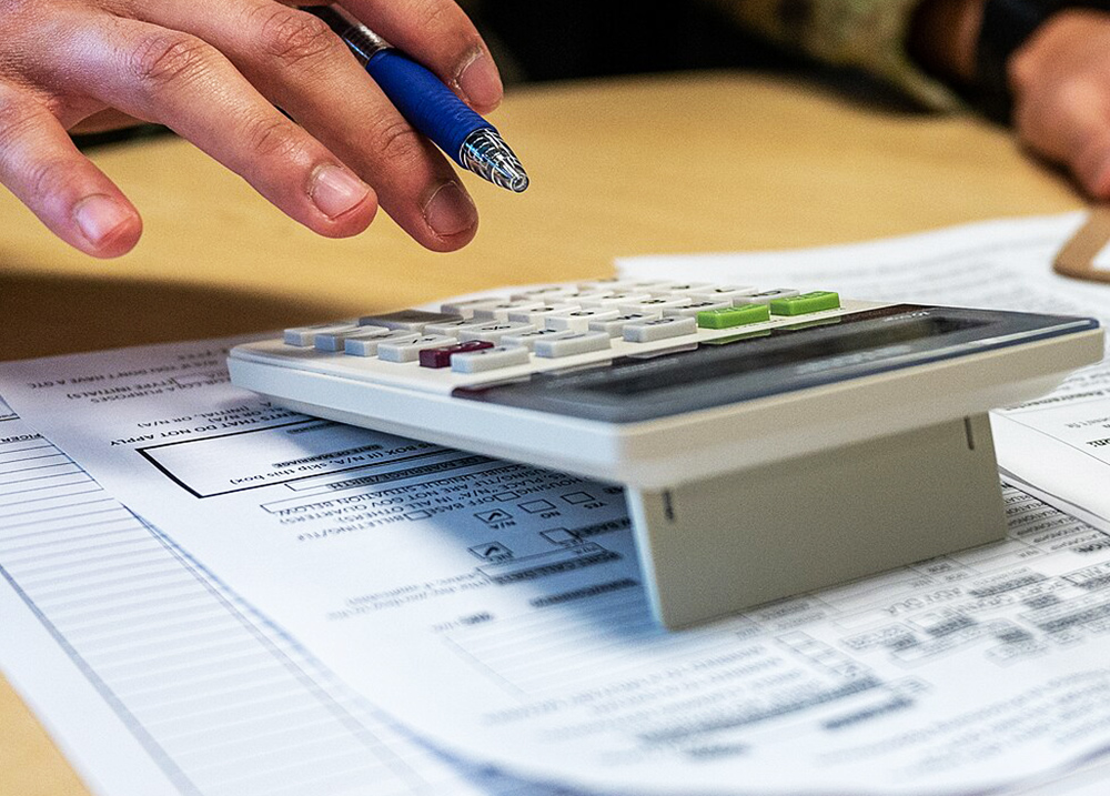 Person holding a pen and using a calculator