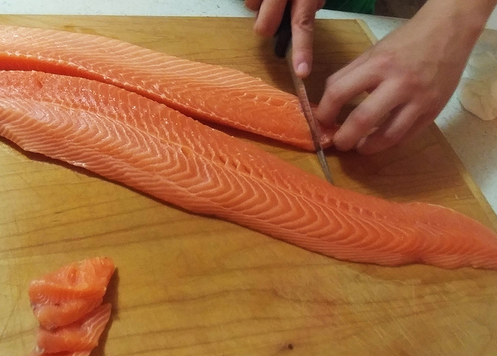 Hands cutting salmon