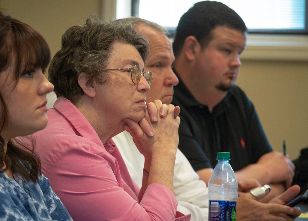 Four people sitting at a table listening to someone out of frame