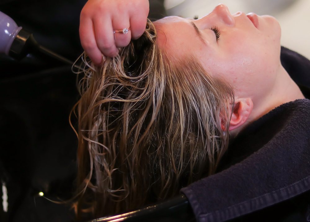 Woman in a salon chair laying back getting her hair dried