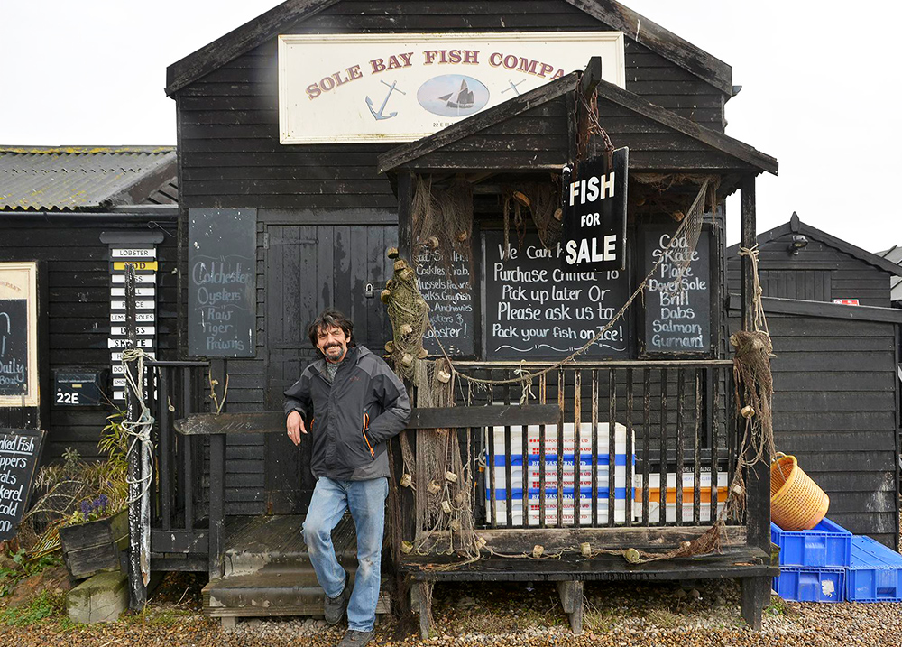 Man smiling and leaning against a business called Sole Bay Fish Company